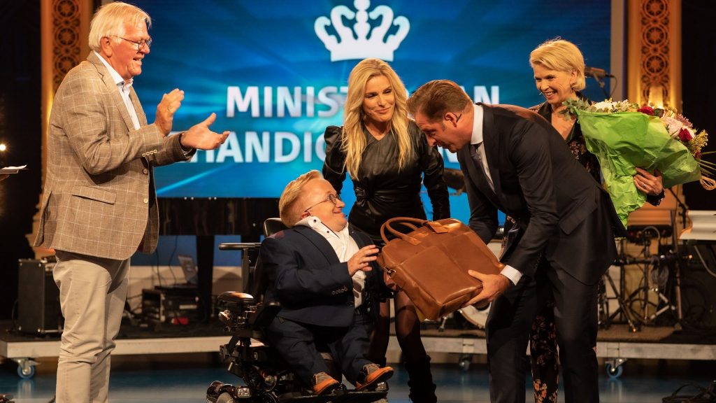 Rick is de nieuwe minister van gehandicaptenzaken en neemt zijn prijs in ontvangst.