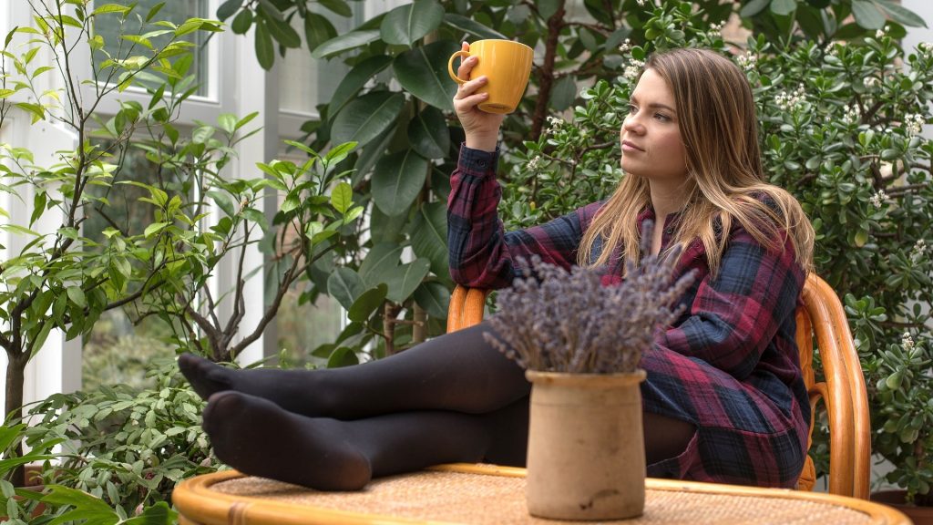 Een meisje lekker lui in de tuin met kopje koffie.