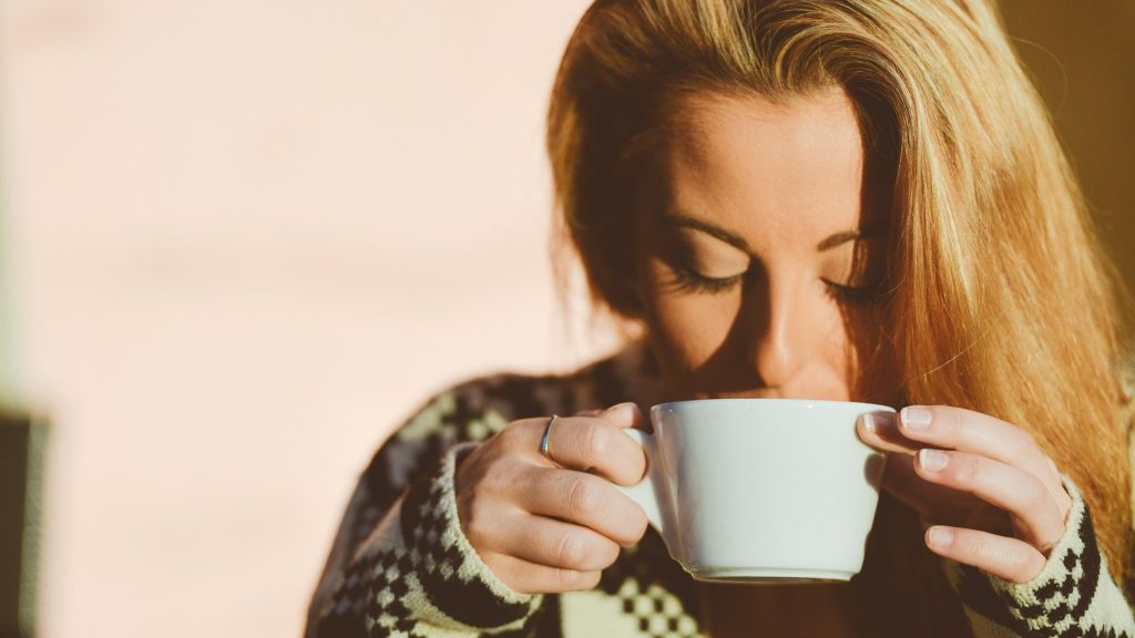 Een vrouw die wakker wordt na het slapen met een kopje koffie. gedoe