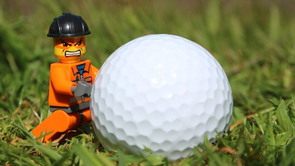 Gefrustreerd lego minifig die tegen een golfbal duwt omdat hok zijn gedachten niet kan loslaten.