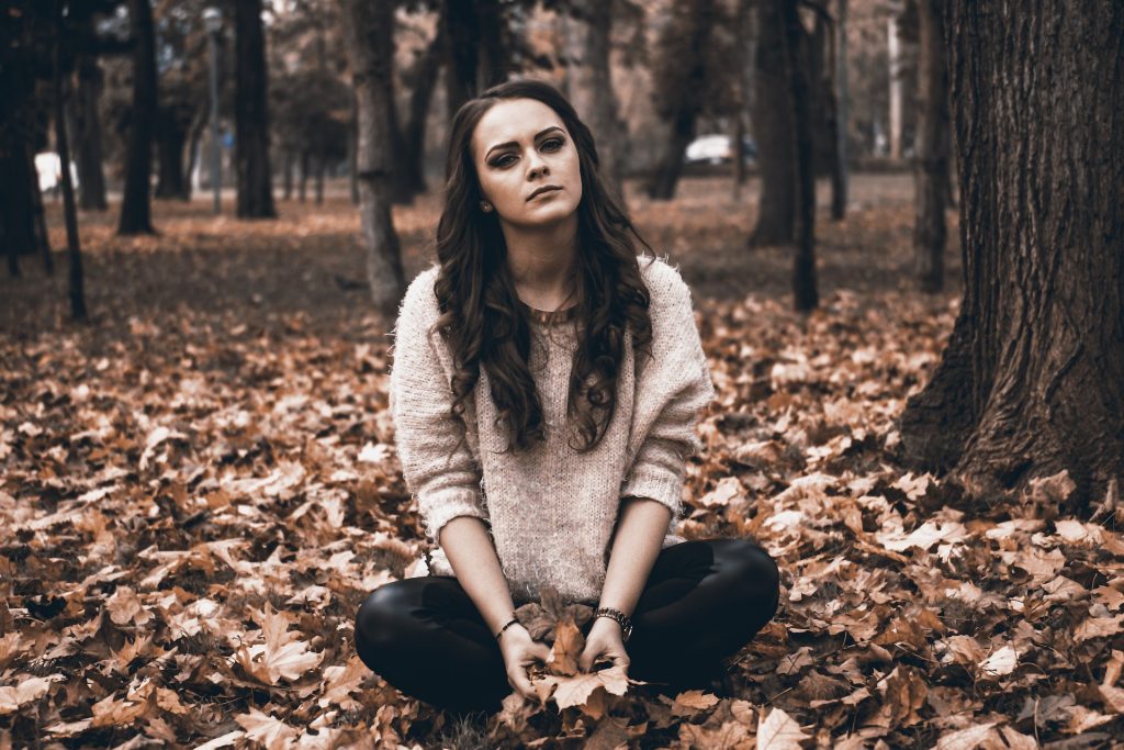 Vrouw met stress in een bos met bruine bladeren op de grond.